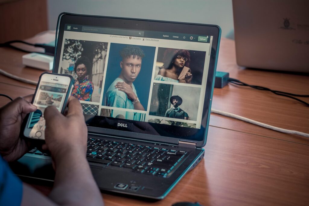A person viewing portrait photos on a Dell laptop and smartphone, indoors.