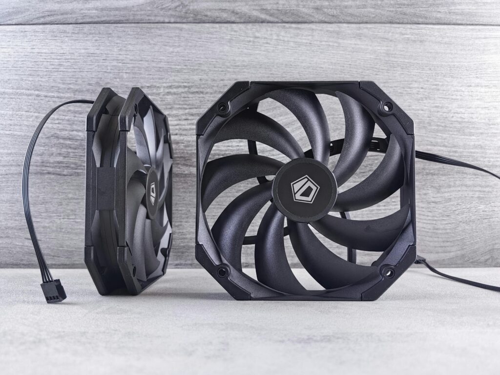 Close-up of two black computer cooling fans on a gray surface, showcasing modern hardware design.