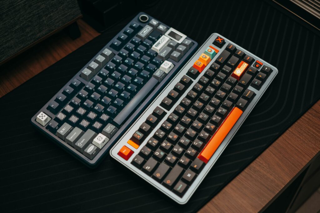 Modern mechanical keyboards with custom keycaps on a wooden desk. Perfect for tech enthusiasts.