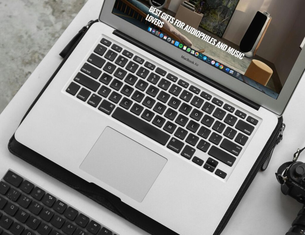 Overhead view of a modern workspace featuring a laptop, camera, and accessories.