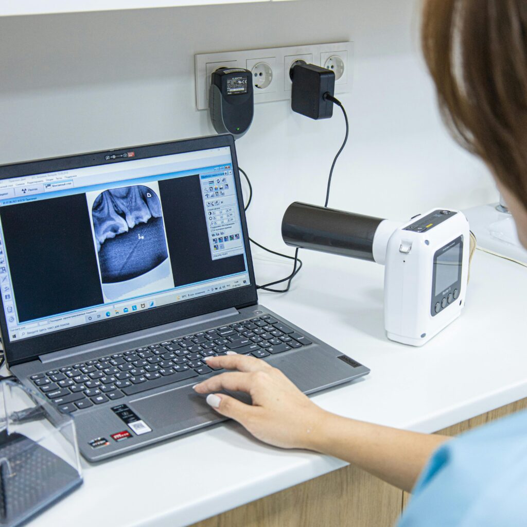 Medical professional analyzing dental X-ray on laptop in modern clinic.