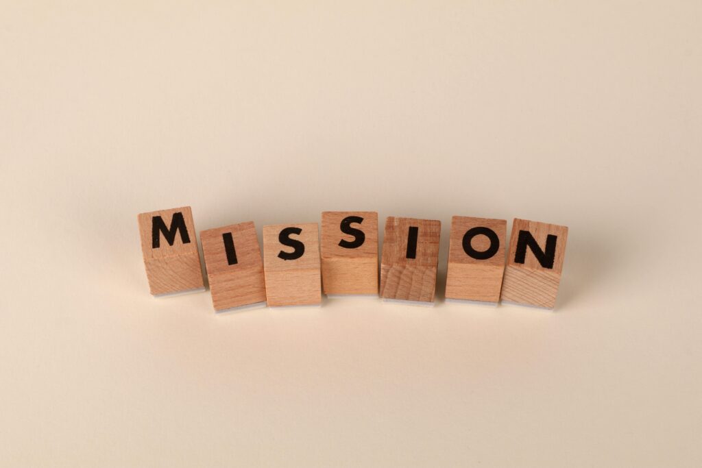 Wooden blocks with letters spelling 'MISSION' against a neutral beige backdrop.